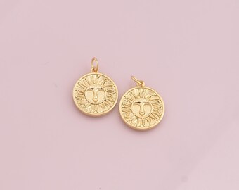 May include: Two gold-toned sun charm pendants with a face in the center. The charms are round and have a textured surface.