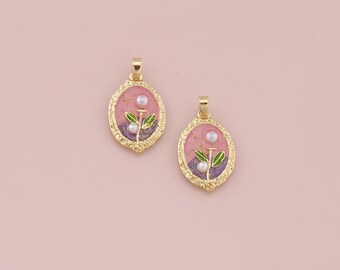 May include: Two gold oval pendants with a pink and purple enamel background. Each pendant features a small green flower with white pearl accents.