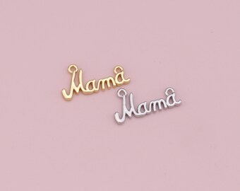May include: Two metal charms, one gold-colored and one silver-colored, each spelling the word "Mama" in a cursive script. The charms are displayed on a light pink background, suitable for jewelry making or crafting.