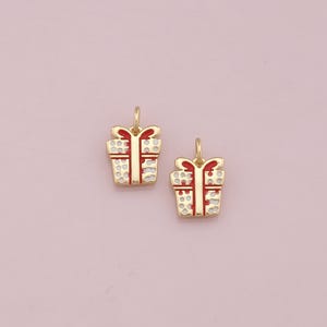 May include: Two gold-colored gift box charms with red ribbon and white polka dots.