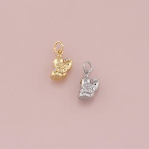 May include: Two gold and silver charm pendants in the shape of a cactus with a small diamond on each.