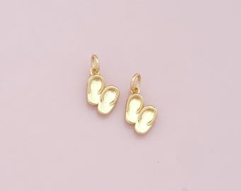 Puede incluir: Dos abalorios de color dorado en forma de chanclas, cada uno con un bucle para sujetar a un collar o pulsera.