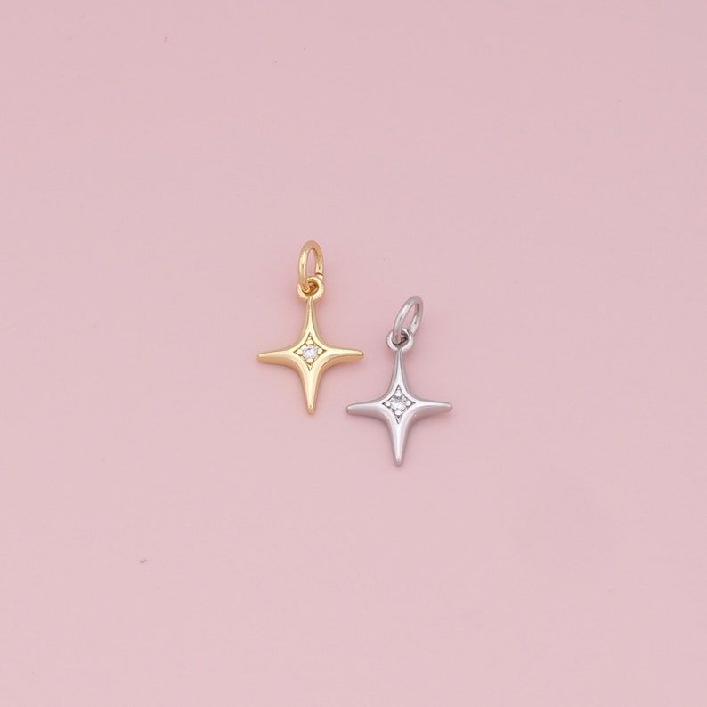 May include: Two star-shaped charms with a single clear stone in the center. The charm on the left is gold and the charm on the right is silver.
