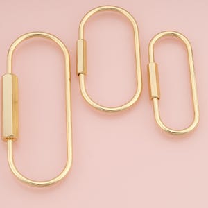 May include: Three gold-toned metal carabiners of varying sizes, each featuring an elongated oval shape and a smooth, polished finish. Each carabiner includes a functional, hexagonal-shaped screw-gate locking mechanism on one side.