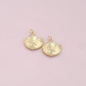 May include: Two gold-tone shell-shaped charms with white pearl accents and clear rhinestone embellishments.