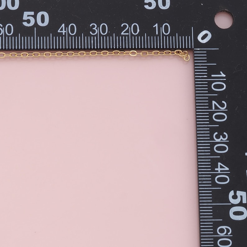K&ouml;nnte beinhalten: Nahaufnahme einer goldenen Kettenkette, die an einem schwarzen Lineal gemessen wird. Die Kette ist etwa 45,7 cm lang.
