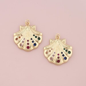 May include: Two gold-tone seashell charms with colorful rhinestones. The charms are perfect for jewelry making or adding a touch of whimsy to any project.