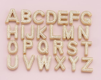 May include: Gold-tone alphabet letter charms with clear cubic zirconia stones. Each letter is individually crafted and features a detailed design.
