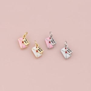 May include: Four small charms shaped like envelopes, each with a tiny card that reads "I love you." Two charms have gold-colored findings, and two have silver-colored findings. The envelopes are pink and white.