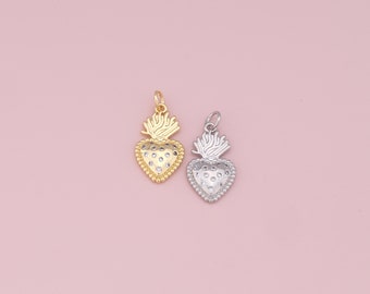 May include: Two gold and silver heart-shaped charms with a flame design. The charms are on a pink background.