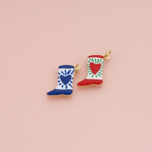 May include: Two metal charms shaped like cowboy boots with gold-tone loops. One boot is white with a blue heart and blue radiating lines. The other boot is white with a red heart and green radiating lines, featuring a solid red foot section.
