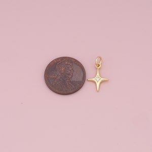May include: Gold star charm with a single clear rhinestone in the center. The charm is about the size of a US penny.