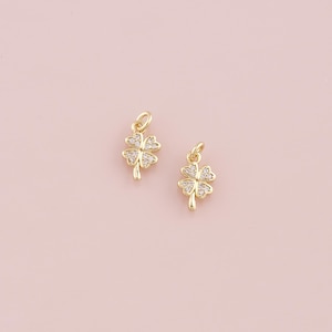Puede incluir: Dos encantos de trébol de cuatro hojas de tono dorado con acentos de cristal transparente.
