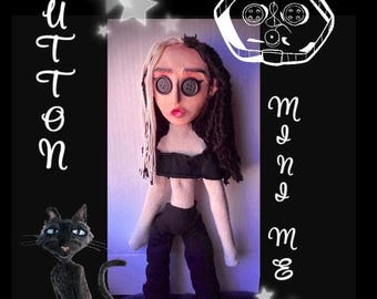 May include: A handmade doll with button eyes, black and white hair, and a black outfit. The doll is posed with a black cat and the word "Button" in script. The background is black with white stars and text.