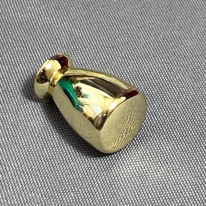 Könnte beinhalten: Ein goldfarbener, tropfenförmiger Schrank-Knopf mit glatter, glänzender Oberfläche.