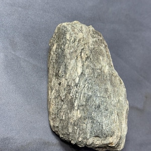 Peut inclure: Une roche rugueuse, grise et blanche avec une surface texturée.