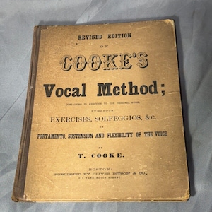 以下が含まれることがあります： 改訂版のラベルが付いた「Cooke's Vocal Method」というタイトルのヴィンテージブック。この本は、金色の文字で茶色の革に製本されており、著者であるT. Cookeと出版社であるOliver Ditson & Co.、ボストンが記載されています。