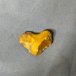 May include: A heart-shaped yellow and brown stone with a rough, natural texture.