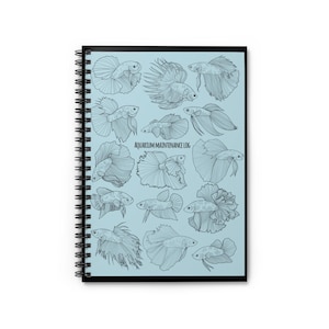 Könnte beinhalten: Spiralgebundenes Notizbuch mit schwarzem Einband und hellblauem Innenraum. Das Notizbuch zeigt detaillierte Schwarz-Weiß-Illustrationen verschiedener Betta-Fische. Der Text "Aquarium Maintenance Log" ist im Inneren des Notizbuchs aufgedruckt.