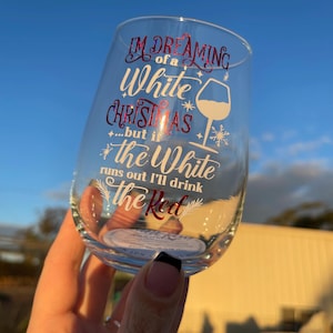 May include: A clear stemless wine glass with the text "I'm dreaming of a White Christmas...but if the White runs out I'll drink the Red" in red and white script. A wine glass and snowflake graphic are also included.