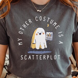 Może przedstawiać: Ciemnoszara koszulka z napisem "MY OTHER COSTUME IS A SCATTERPLOT" i kreskówkowym duchem trzymającym wykres. Koszulka ma wygodny krój i krótkie rękawy.