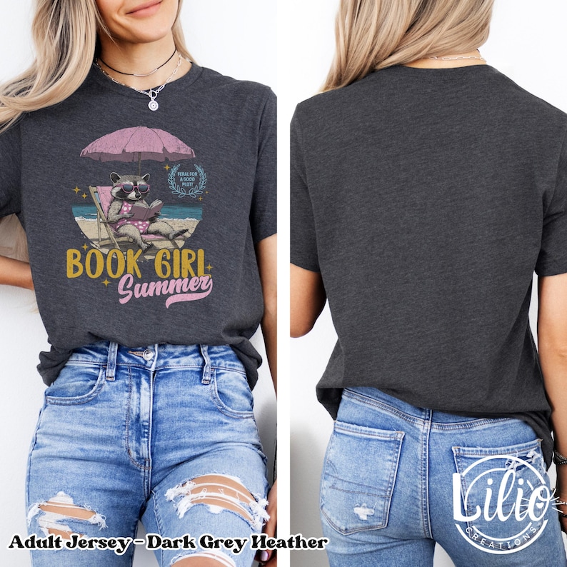 May include: Dark grey heather adult jersey t-shirt with a graphic of a raccoon wearing sunglasses and reading a book on a beach chair under an umbrella. The text "Book Girl Summer" is printed on the shirt.