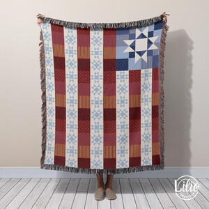 May include: A woven throw blanket with a patriotic design. The blanket features a patchwork pattern with red, white, and blue sections, including stars and stripes. The edges are finished with a fringe.