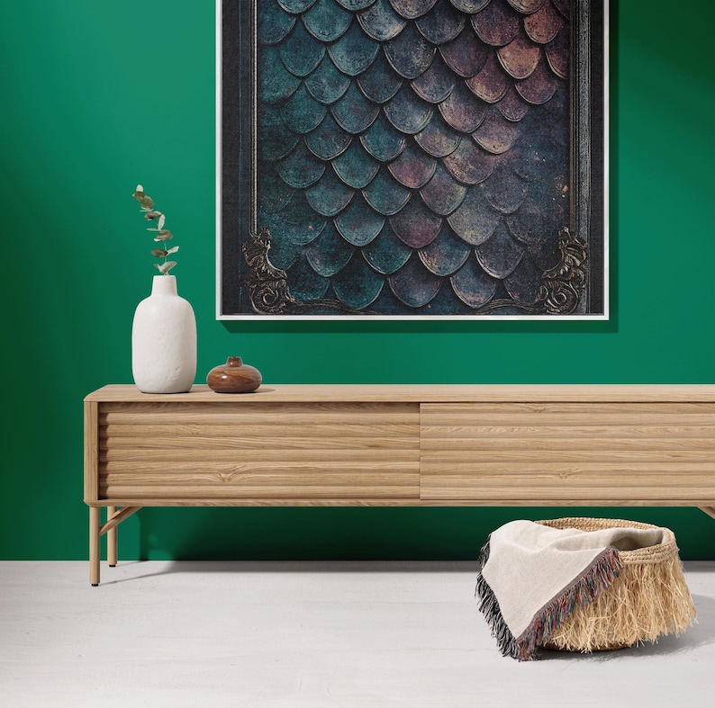 K&ouml;nnte beinhalten: Eine helle Holz-Medienkonsole mit zwei T&uuml;ren und einem geflochtenen Korb mit einem Fransenwurf auf einem wei&szlig;en Boden vor einer gr&uuml;nen Wand mit einem gerahmten Druck eines bunten Schuppenmusters.