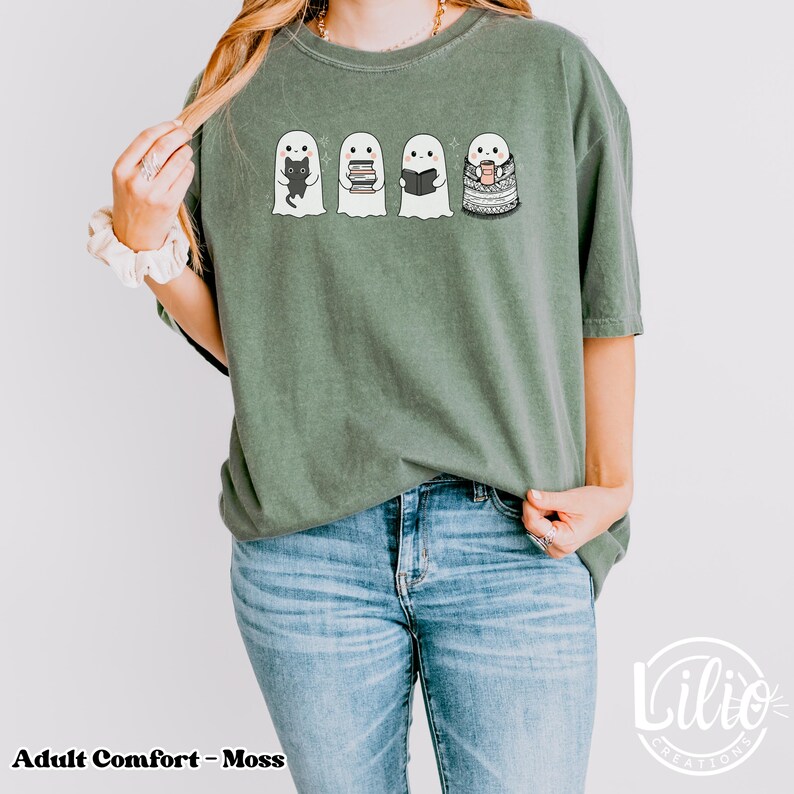 Pode incluir: Camiseta verde musgo com quatro fantasmas de desenho animado. Cada fantasma tem um design diferente: um gato preto, livros, um livro aberto e uma x&iacute;cara de caf&eacute;. O texto "Adult Comfort - Moss" est&aacute; na parte inferior esquerda.