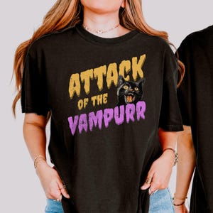 May include: Black t-shirt with a graphic print of a black cat with the text "Attack of the Vampurr" in yellow and purple.