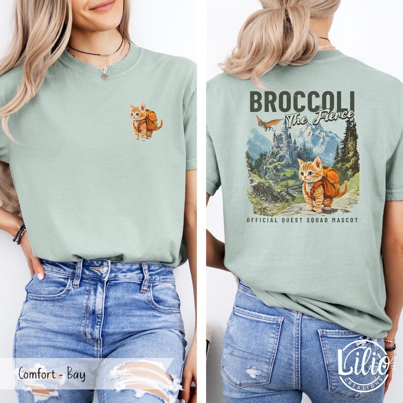 May include: A light green t-shirt with a graphic of a cat wearing a backpack and the text "Broccoli The Fierce" on the back. The cat is standing on a path in a mountainous landscape. The text "Official Quest Squad Mascot" is below the graphic.