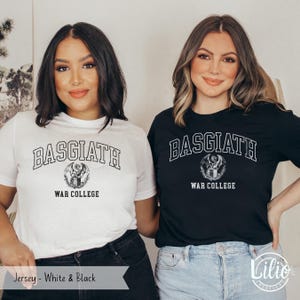 K&ouml;nnte beinhalten: Zwei Personen tragen wei&szlig;e und schwarze T-Shirts. Das wei&szlig;e Shirt hat den Text "BASGIATH WAR COLLEGE" in einer College-Schriftart mit einem Drachenemblem. Das schwarze Shirt hat das gleiche Design. Der untere Teil des Bildes lautet "Jersey - Wei&szlig; & Schwarz".
