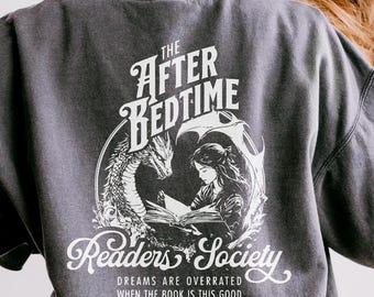 Może przedstawiać: Szara bluza z nadrukiem w kolorze białym przedstawiającym smoka, dziewczynę czytającą książkę i tekst "The After Bedtime Readers Society. Dreams are overrated when the book is this good."