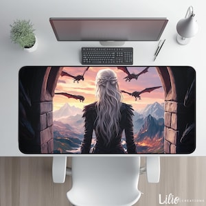 Könnte beinhalten: Rechteckige Schreibtischunterlage mit einer Fantasy-Szene, die eine Frau mit langen weißen Haaren zeigt, die eine Berglandschaft mit Drachen betrachtet. Die Matte hat einen dunklen Rand und liegt auf einem weißen Schreibtisch mit Tastatur, Monitor und Schreibtischlampe.