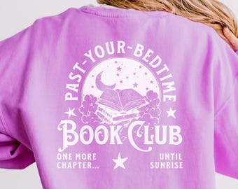 Może przedstawiać: Fioletowa bluza z białym nadrukiem, na którym widnieje napis "Past Your Bedtime Book Club" z półksiężycem, gwiazdami i stosem książek. Tekst pod grafiką brzmi "One More Chapter... Until Sunrise."