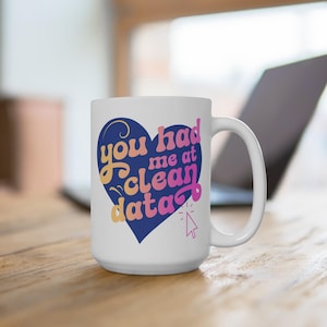 May include: White ceramic mug with a blue heart design. The heart has the text "You had me at clean data" in pink and yellow lettering with a cursor icon.