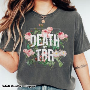 May include: A gray t-shirt with a floral design and the text "Death by TBR" in white letters.