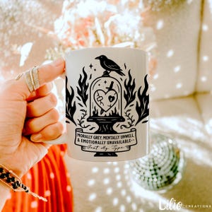 Puede incluir: Taza de cerámica blanca con una ilustración en blanco y negro de un pájaro en una jaula con un corazón roto en su interior. El texto dice "Morally Grey, Mentally Unwell, & Emotionally Unavailable - Just My Type - "