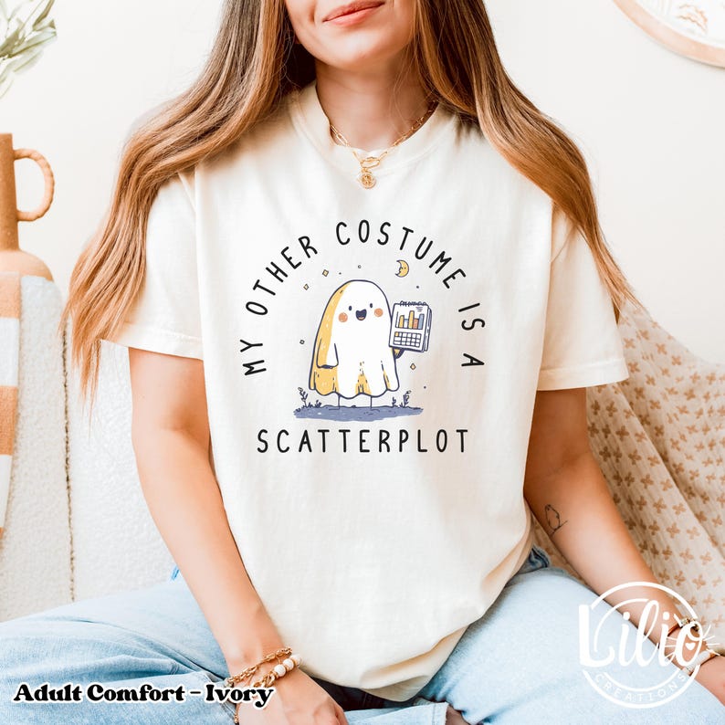 Pode incluir: Camiseta cor marfim com o texto "MY OTHER COSTUME IS A SCATTERPLOT" e um fantasma de desenho animado segurando um gr&aacute;fico. A camiseta &eacute; de ajuste confort&aacute;vel, para adultos.