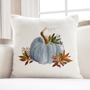 May include: A white throw pillow with a blue watercolor pumpkin and fall foliage design.
