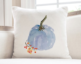 May include: A white throw pillow with a watercolor painting of a blue pumpkin and red berries.