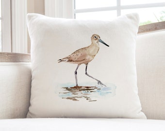 May include: A white throw pillow with a watercolor illustration of a brown shorebird standing in shallow water.