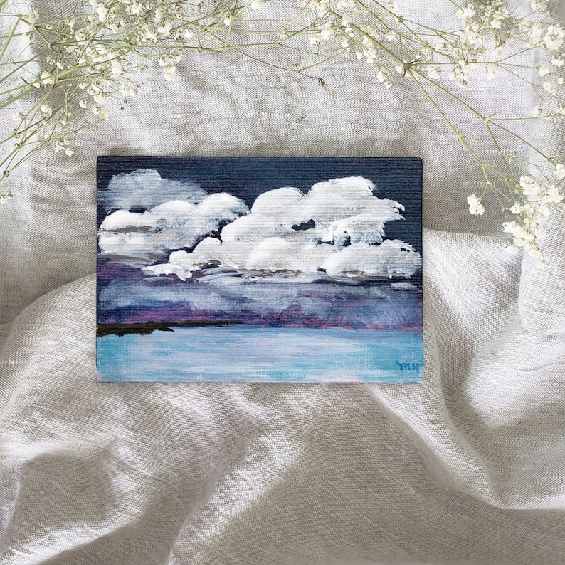 Puede incluir: Peque&ntilde;a pintura rectangular que representa un cielo nublado sobre el agua. El cielo es azul marino con nubes blancas. El agua es azul claro y el horizonte tiene un tono p&uacute;rpura. La pintura est&aacute; firmada en la esquina inferior derecha.