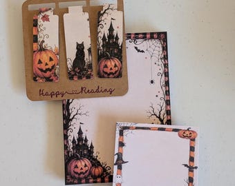 Può includere: Un set di tre segnalibri magnetici rettangolari su un cartoncino marrone con la scritta Happy Reading, insieme a un blocco note alto e uno quadrato. Entrambi i blocchi presentano illustrazioni di Halloween con zucche, castello, pipistrelli e ragnatela.
