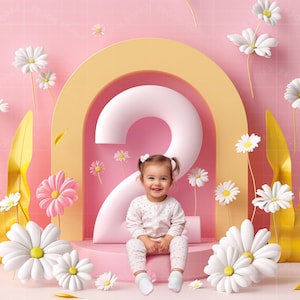 Puede incluir: Un número dos rosa y blanco con un niño pequeño sentado delante. El niño lleva una camisa y pantalones con estampado blanco y rosa. El fondo es rosa con flores blancas.