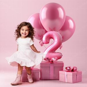 Puede incluir: Una niña sonriente con un vestido blanco y botas rosas posa frente a globos rosas y cajas de regalo. También hay un gran globo rosa con el número 2, sugiriendo una celebración de cumpleaños.