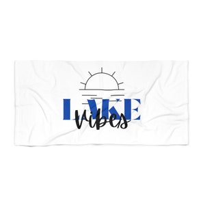 May include: White beach towel with a blue and black graphic that says "LAKE vibes" with a stylized sun and water design.