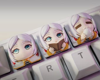 May include: Three white anime-style keycaps with different expressions. The keycaps are on a white keyboard with black keys. The keycaps feature a girl with a book, a girl with a cup, and a girl with a neutral expression.