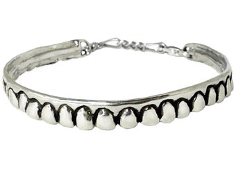 May include: A silver bangle bracelet with a row of small, rounded bumps along the top edge.