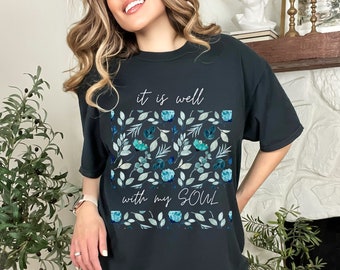 May include: Black t-shirt with a floral design and the text "it is well with my soul" in white.